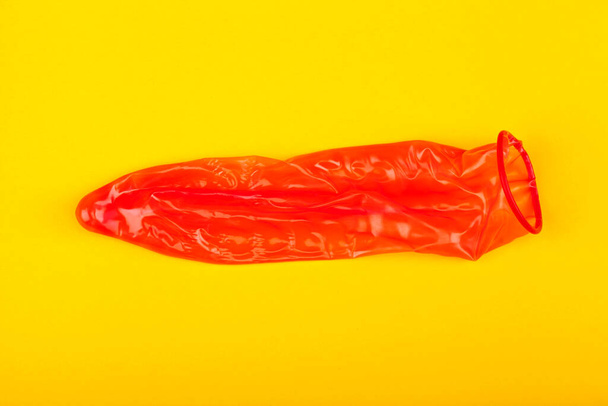 picture of a red condom on yellow background - Fotoğraf, Görsel