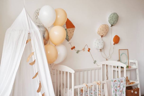 Scandinavian style white interior children's room, bedroom, nursery. Baby cot with canopy. Wooden shelves and toys. Canopy tent, textile kite and balloons. - Photo, Image