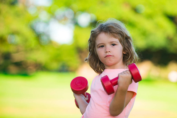 Fitness dumbbells kid exercise workout outdoor. Boy sporty child with dumbbells. Sport portrait kids. - Foto, immagini