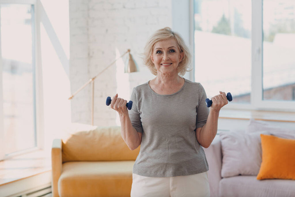 Anciana caucásica anciana retrato gris haciendo ejercicios con pesas. - Foto, Imagen