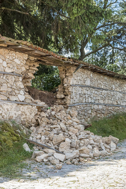 Bulgar köyündeki bir evin taş çitinin bir kısmı kısmen yıkıldı. Duvardaki delik.. - Fotoğraf, Görsel