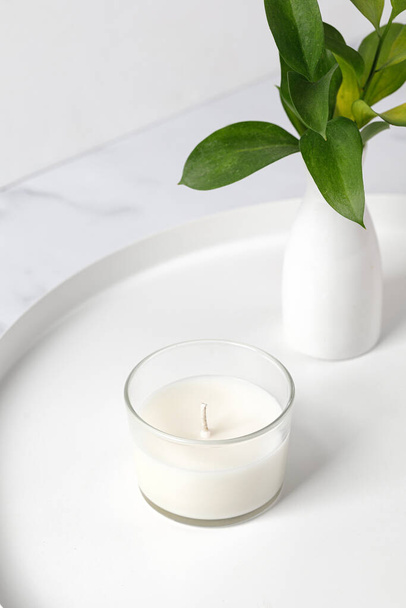 Jars candle with coconut or soy wax on table with vase of green leaves. White interior pfotography - Foto, Imagen