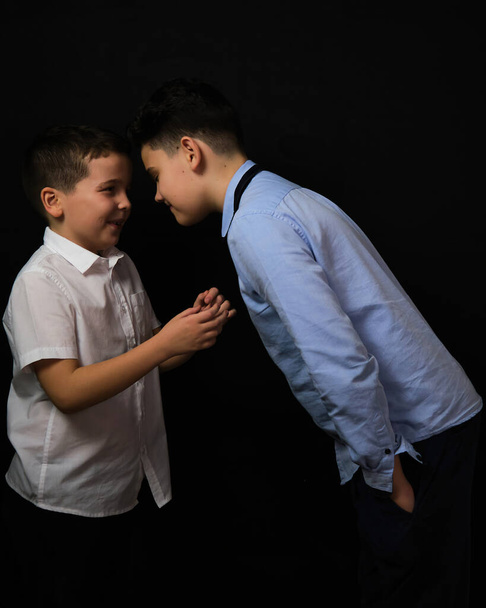 Two boys on a black background are brothers.Senior and junior.Atelier.Reproach, proof - Фото, зображення