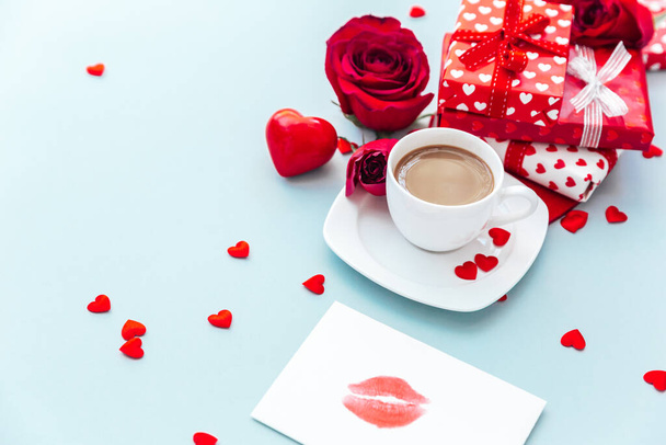 White cup of coffee with gift and roses. morning breakfast. Holiday background. Greeting card. Valentines Womans Mothers day. Top view. Flat lay - 写真・画像