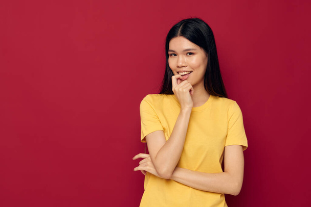 Portré ázsiai gyönyörű fiatal nő egy sárga póló gesztikuláló kezével szórakoztató elszigetelt háttér változatlan - Fotó, kép