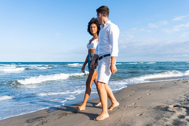 幸せな若いカップルはビーチを歩く-愛の幸せな若いカップルは日没でロマンチックなビーチを歩く-休暇中の恋人-人々は夏のライフスタイルで旅行. - 写真・画像