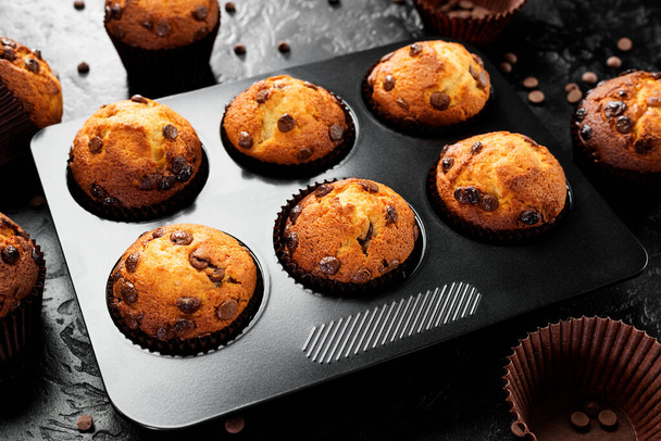 Chocolate chip muffins in baking pan on black background. - Fotó, kép