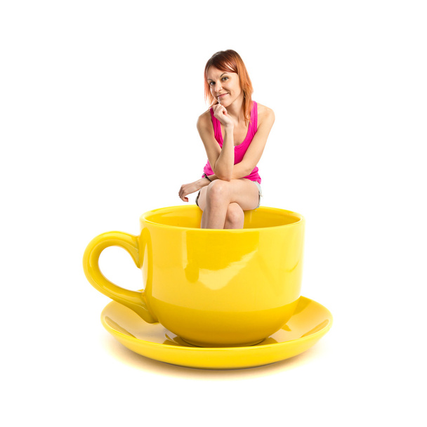 Рыжая девушка сидит на чашке кофе на белом фоне
 - Фото, изображение