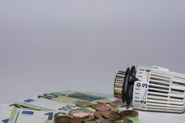 Zvýšení cen energie a spotřeba energie termostatický regulátor z vytápění s 100 euro bankovky a hodně mincí - Fotografie, Obrázek