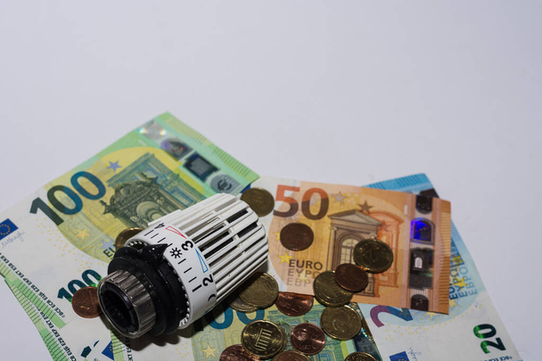 Wzrost cen energii i zużycie energii regulator termostatyczny z ogrzewania z różnych banknotów i monet euro i szarego tła - Zdjęcie, obraz