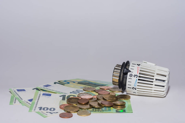エネルギー価格の上昇と100ユーロ札とコイン底のビューで加熱からのエネルギー消費サーモスタットレギュレータ - 写真・画像