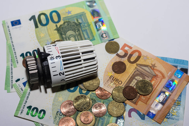 Wzrost cen energii i zużycie energii regulator termostatyczny z ogrzewania z różnych banknotów i monet euro widok szczegółowy - Zdjęcie, obraz