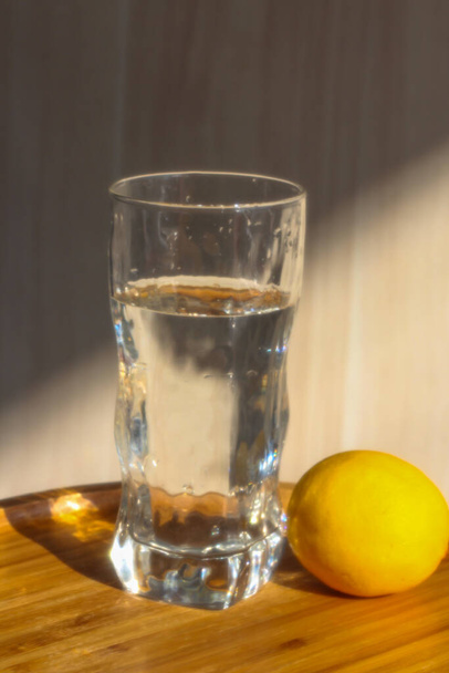 A glass of water and lemon in the morning light - Фото, изображение
