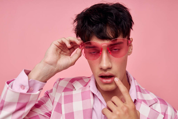A young man fashionable pink sunglasses jacket posing pink background unaltered - Фото, изображение