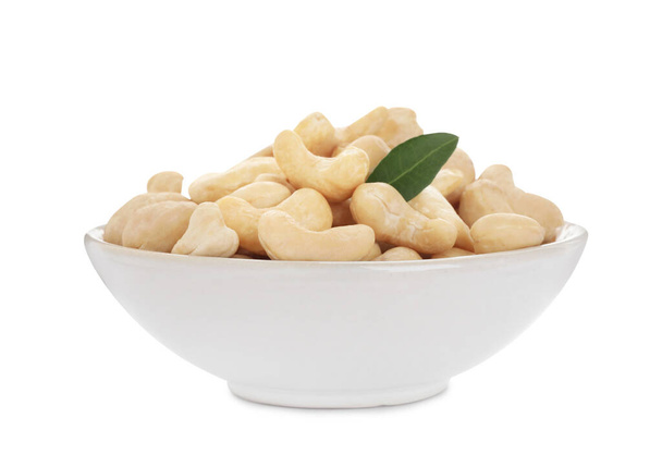 Bowl of tasty organic cashew nuts and green leaf isolated on white - Photo, Image