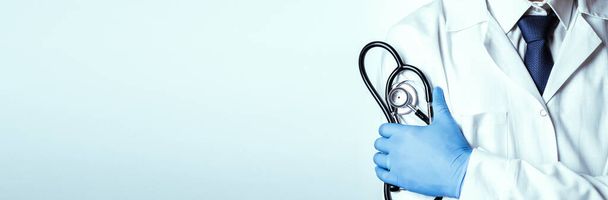 Stethoscoop arts medische achtergrond. Gelukkige verpleegster in ziekenhuisuniform, blauwe handschoenen met stethoscoop geïsoleerd op wit. Geneeskundige dienst en gezondheidszorgconcept - Foto, afbeelding