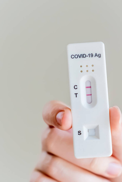 Hände halten Covid-19 Schnellantigentestkassette mit positivem Ergebnis des diagnostischen Schnelltests zu Hause - Foto, Bild