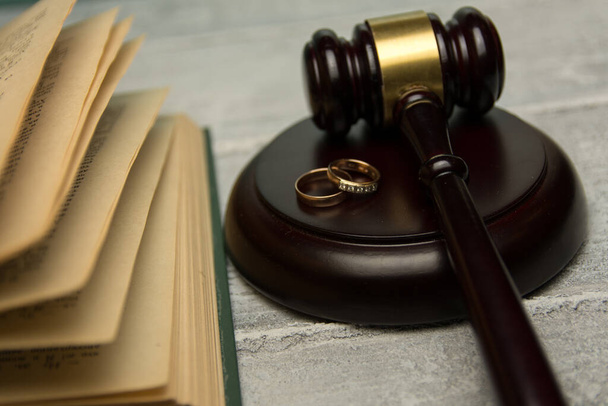 Law and Justice. Judge gavel and wedding rings on concrete background - 写真・画像