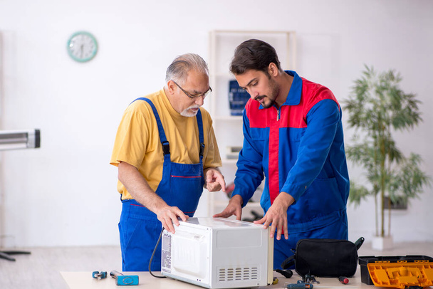 Δύο άνδρες επισκευαστές που εργάζονται στο συνεργείο - Φωτογραφία, εικόνα