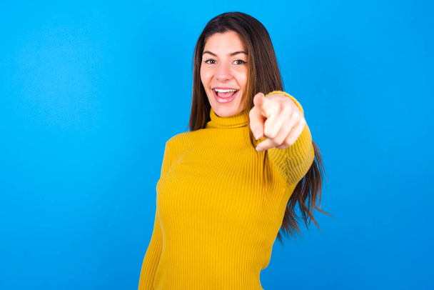 Excited positive  young woman wearing yellow turtleneck sweater  pointing  index finger directly at you, sees something very funny. Wow, amazing - Photo, Image