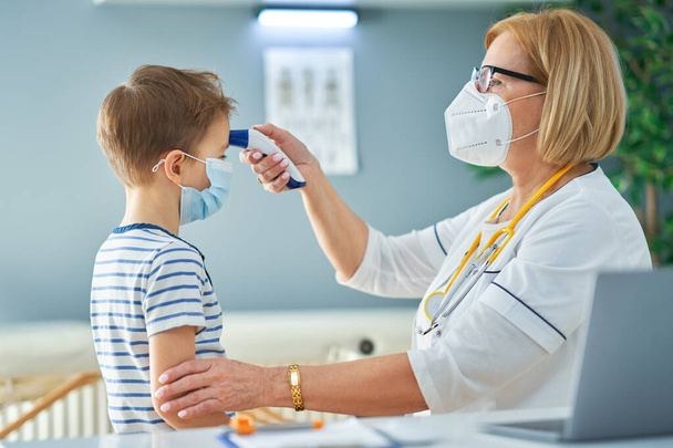 Pediatrician doctor examining little kids in clinic temperature check - Фото, изображение
