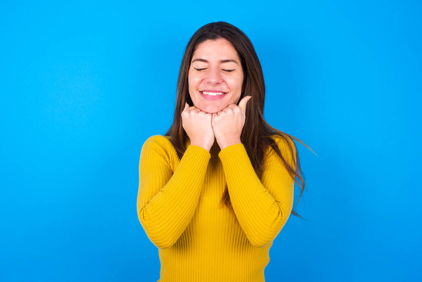 Cheerful  young woman wearing yellow turtleneck sweater   has shy satisfied expression, smiling  broadly, showing  white teeth, People emotions - Photo, Image