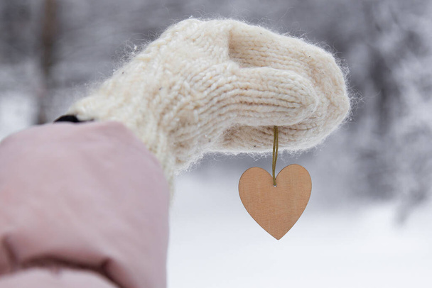 Woman holding wooden heart on winter snow background, close up. Valentines Day concept. - Foto, afbeelding