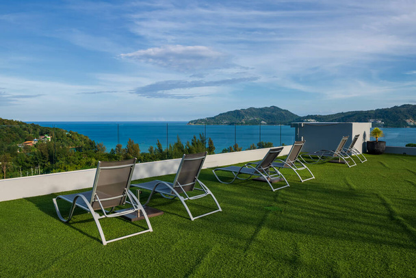 Ligstoelen op luchtbalkon van luxe resort om te genieten van zeegezicht uitzicht op de blauwe hemel, Phuket, Thailand. Reisbestemming of zomervakantie maker in Siam. - Foto, afbeelding