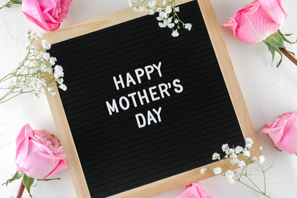Boldog anyák napi SMS-t a fekete betűs táblán. Rózsaszín rózsák, cigányvirág a háttérben. Üdvözlőlap koncepció. Lapos fektetés - Fotó, kép