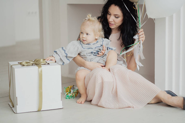 A young beautiful family opens a gift box, a brunette mother and - Foto, imagen