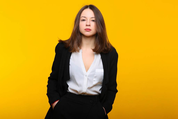 A young woman in a business suit on a yellow background - Фото, зображення