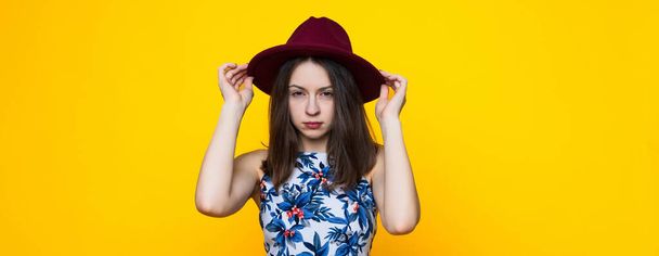 A young woman in a dress and hat on a yellow background - Fotografie, Obrázek