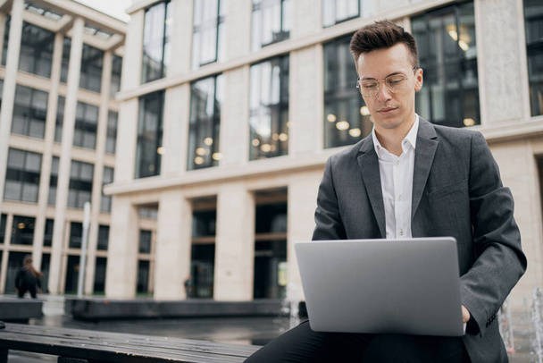 a businesslike young man keeps working on a laptop, typing text  - Zdjęcie, obraz