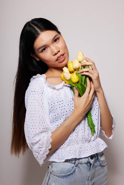 woman with Asian appearance romance bouquet of flowers near the face light background unaltered - 写真・画像