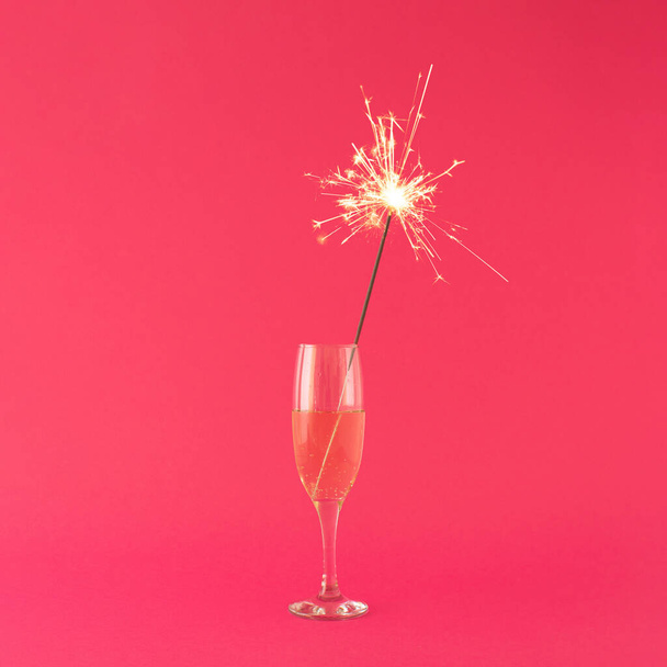 Champagne glass with sparkler on pink background. Minimal party concept. Modern woman concept. - Valokuva, kuva