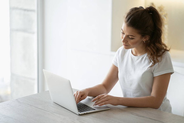 A woman is engaged in online shopping in the website app on a la - Фото, зображення