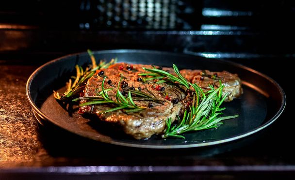 Tasty grilled beef steak in a oven with rosemary and pepper - Foto, Bild
