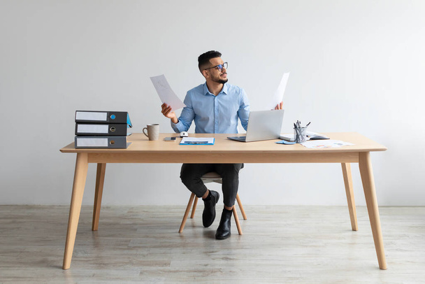 Hombre sosteniendo el informe de lectura de papel trabajando en el ordenador portátil en la oficina - Foto, Imagen
