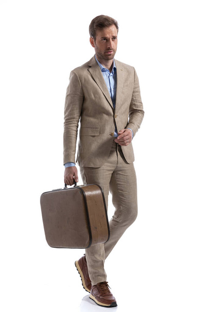 attractive businessman walking on his way and holding a briefcase against white studio background - Foto, imagen
