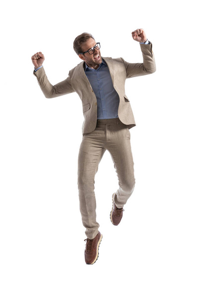 opgewonden zakenman springen en het verhogen van zijn armen in de lucht, vieren en het dragen van bril - Foto, afbeelding