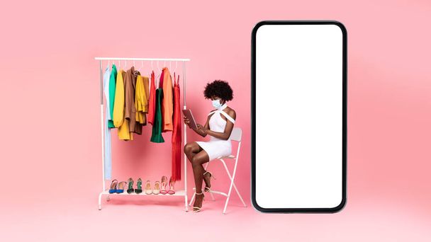 Dama negra cerca de teléfono enorme usando las compras de la tableta, fondo rosa - Foto, imagen