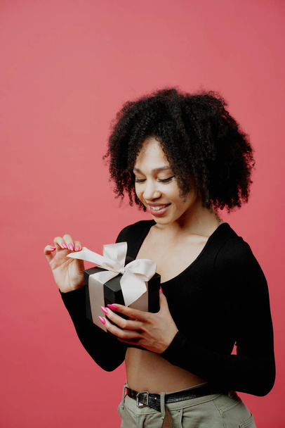 Positive mood. shows holding a black gift box with a bow . young - Foto, immagini