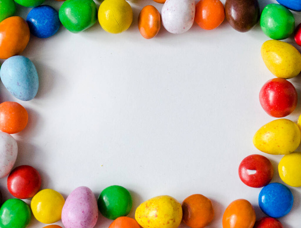 Küçük, çikolata, çok renkli şekerler beyaz arkaplan üzerinde çerçeve şeklinde ortada yazı yazmak için alan - Fotoğraf, Görsel