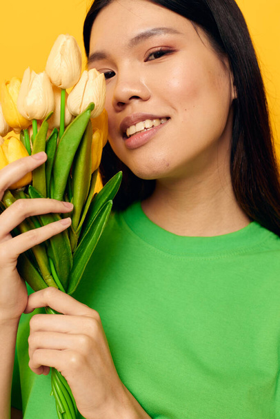 pretty brunette green t-shirt a bouquet of yellow flowers isolated background unaltered - Fotó, kép
