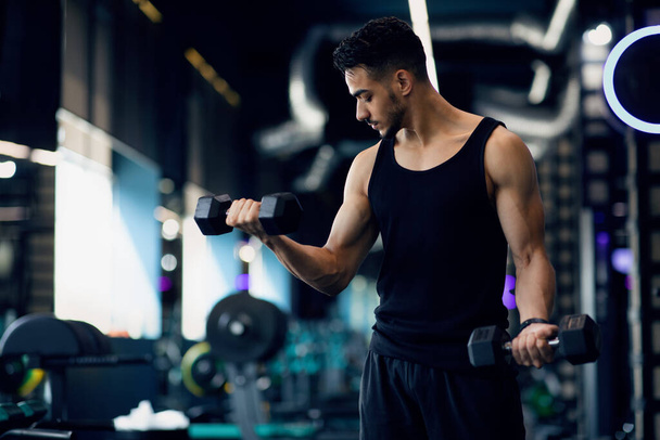 Portrait de la formation masculine jeune Moyen-Orient bodybuilder avec haltères à la salle de gym - Photo, image