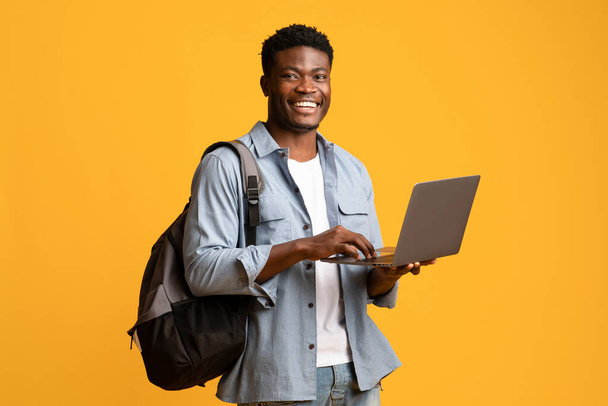 Iloinen afrikkalainen amerikkalainen miespuolinen opiskelija kannettavan tietokoneen avulla - Valokuva, kuva