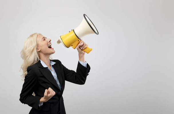 Эмоциональная деловая женщина кричит с громкоговорителем, делает рекламу или объявление о продаже или скидке - Фото, изображение