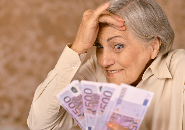 Aged woman holding euros - 写真・画像