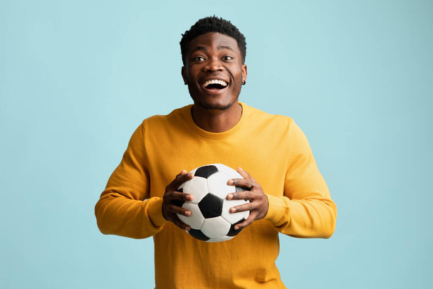 Happy black guy with soccer ball posing on blue - Foto, immagini