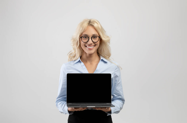 Щаслива молода бізнес-леді тримає ноутбук з порожнім екраном для вашого оголошення або дизайну веб-сайту
 - Фото, зображення